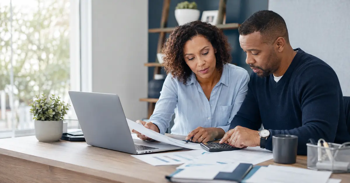 American couple using a calculator and reviewing 2026 federal tax planning documents at home